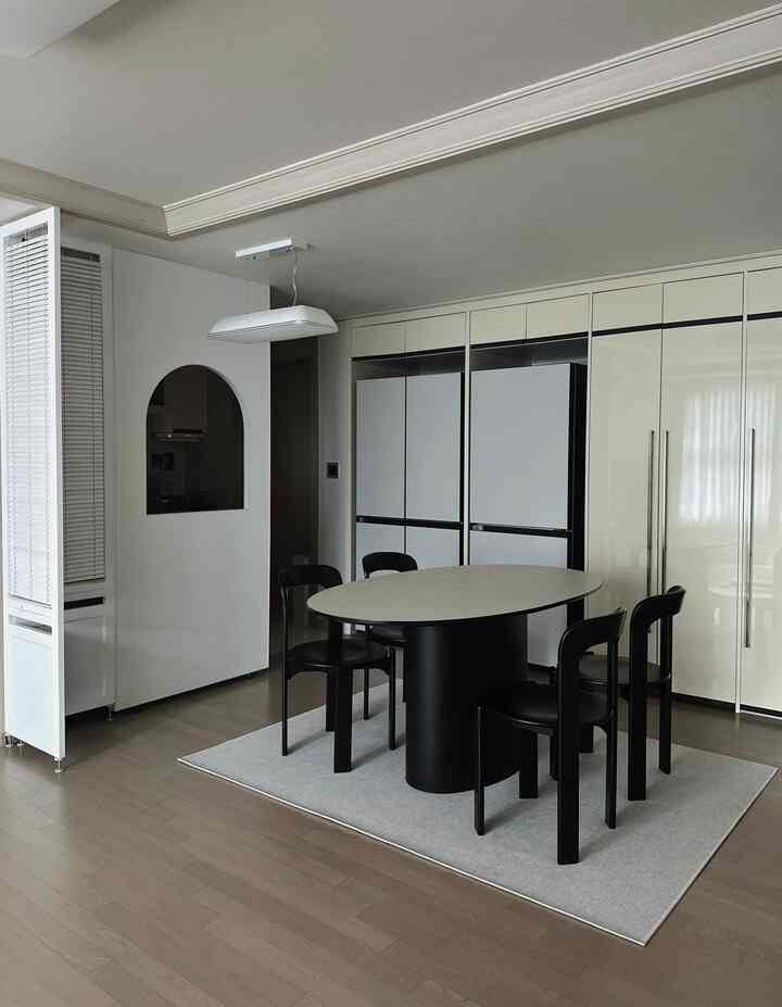 モノトーンでシンプルなダイニングルーム、アーチ型パーティションとブラインドが空間を分ける雰囲気のあるインテリア