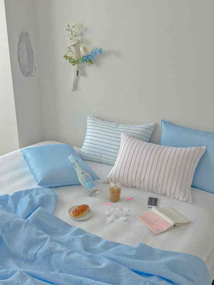 Cool blue and white bedroom featuring striped pillows and crisp bedding in a clean, refreshing space