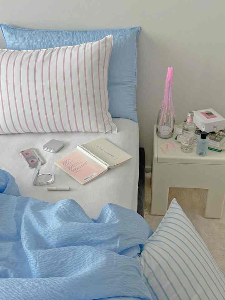 Pastel blue and white toned bedroom featuring textured blue bedding and striped pillows, creating a cozy atmosphere