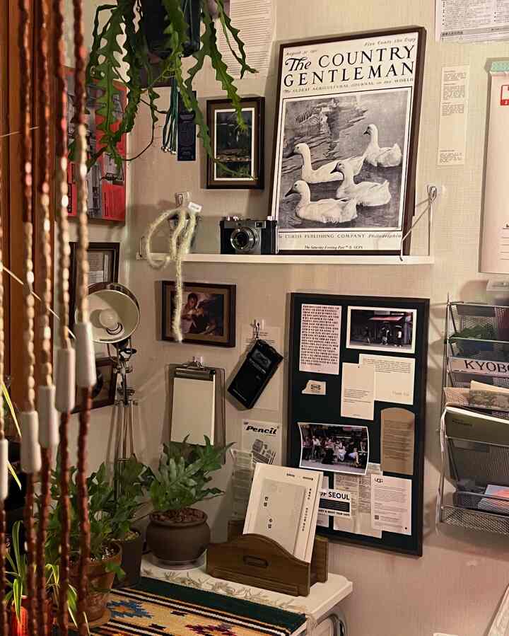 ベージュとナチュラルカラーの狭い部屋、ヴィンテージの額縁と植物が配された雰囲気のあるインテリア