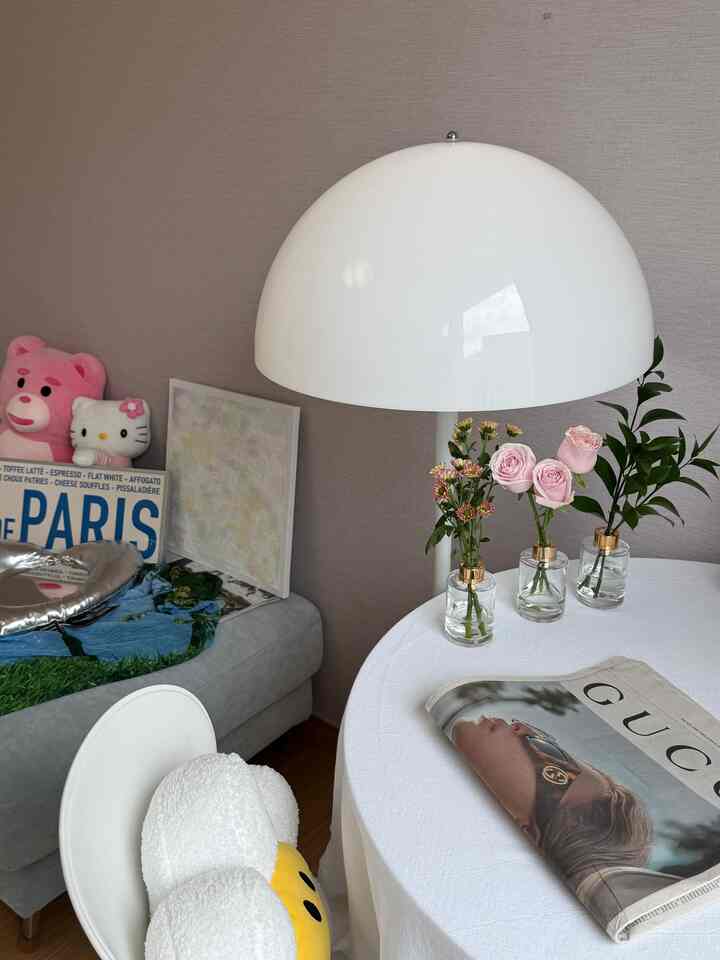 白を基調としたリビングのおうちカフェ、丸い白いテーブルとドーム型フロアランプ、花やクッションがポイントの温かみのあるインテリア