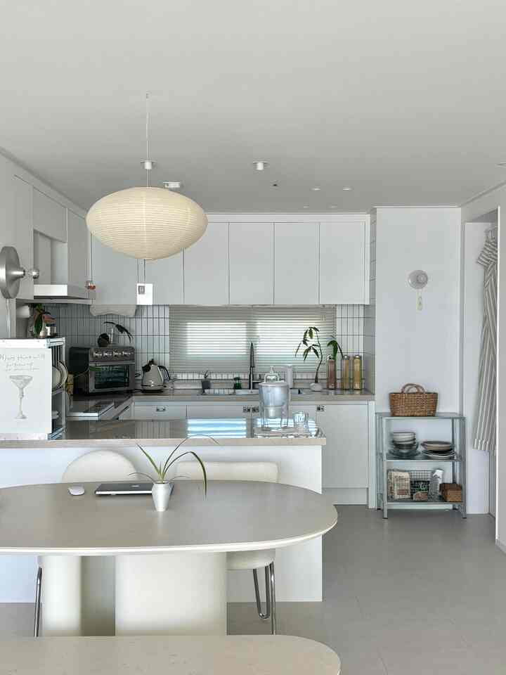 明るいホワイトと木目調が調和したミニマルな30坪のキッチン、セラミックダイニングテーブルと照明が配置された印象的な空間