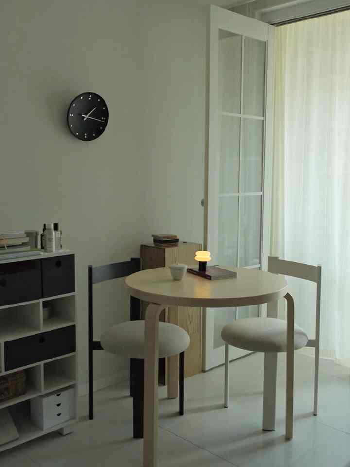 白と木目調の小さなダイニングルーム、丸いダイニングテーブルと二脚の椅子がシンプルモダンな雰囲気を演出している。