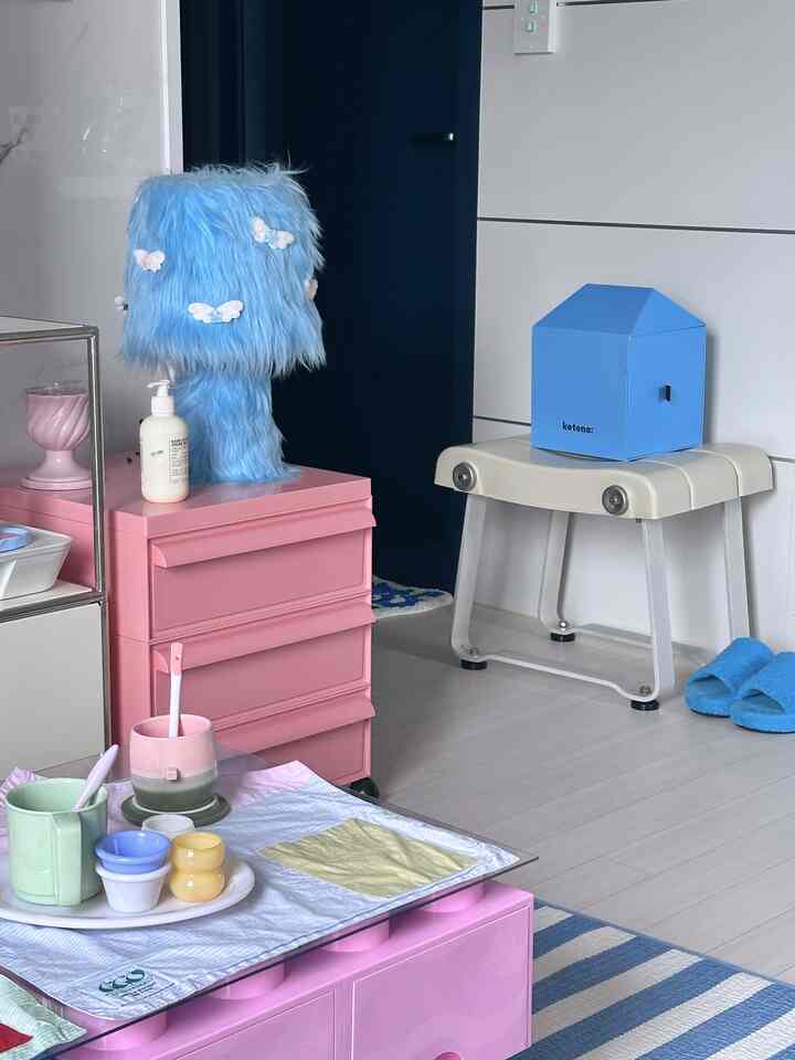 パステルピンクとブルーの調和が取れた空間、ふわふわのファーランプと小物が配置された印象的なインテリア