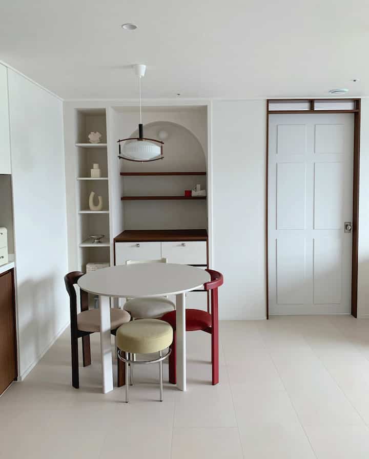 White and wood tone dining room featuring a round table with various accent chairs in a simple home cafe setting