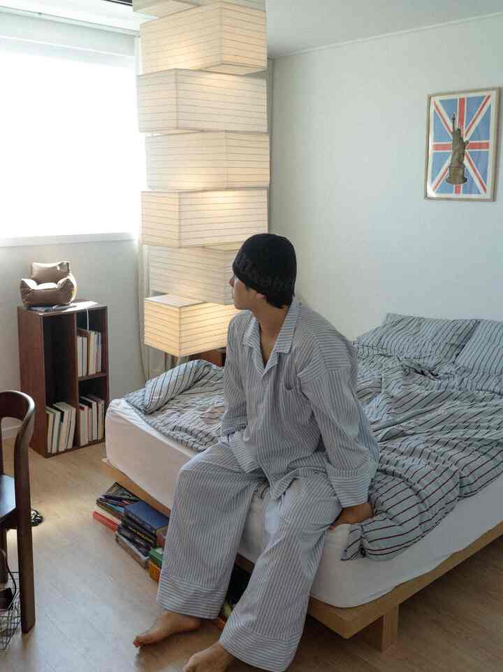 ナチュラルカラーと木目調の寝室、シンプルなベッドとストライプ寝具が調和した落ち着いた空間