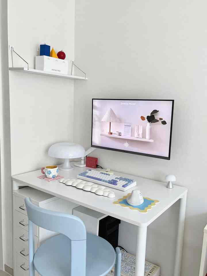 白とスカイブルーのトーンでまとめられたコンパクトでミニマルなホームオフィス、整然としたデスクと壁掛けモニターが配置された作業空間