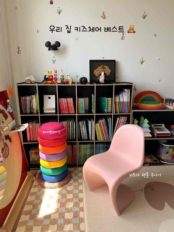 温かみのあるナチュラルカラーと木製家具が調和した子供部屋。ピンクのヴィトラ パントン ジュニアチェアとカラフルなスツールが印象的な雰囲気を演出する空間