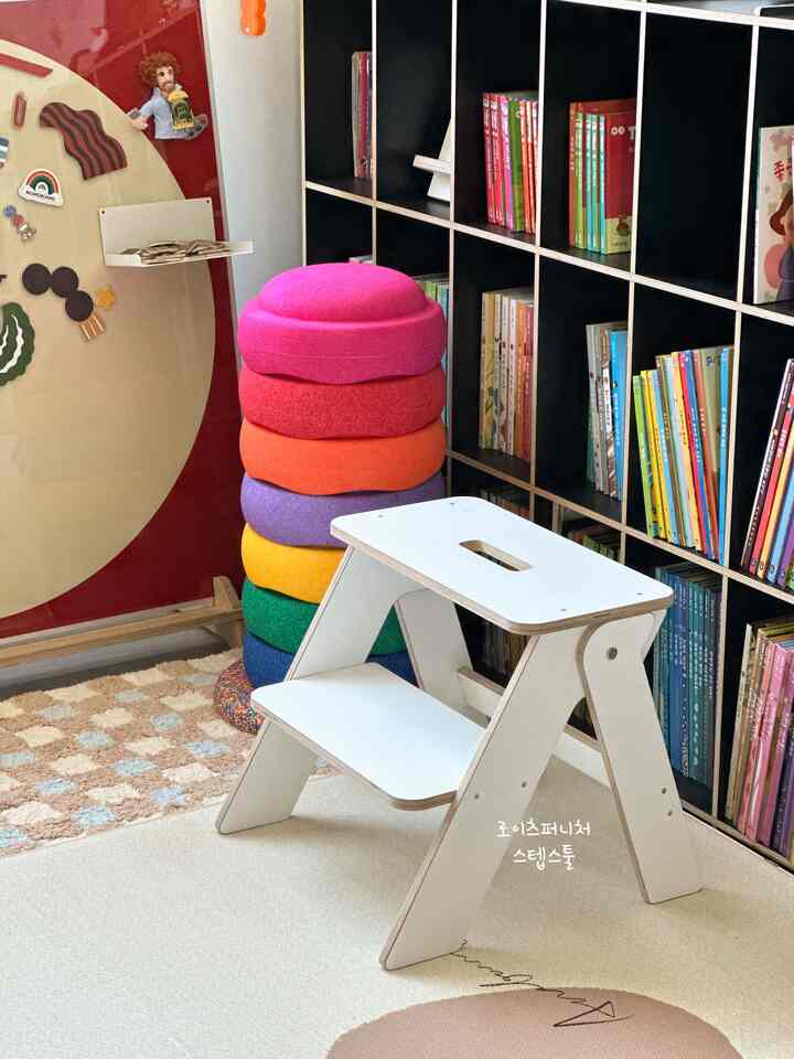 ナチュラルな色調と白い家具、書棚が配置された子供部屋の内装