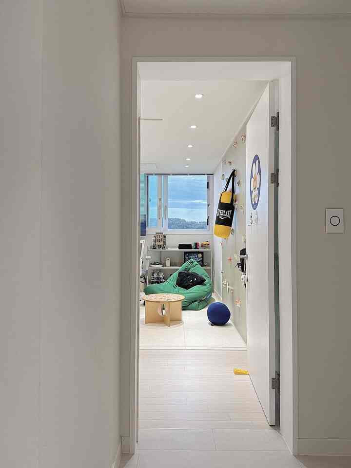 白と緑の色調の子供部屋、ビーズクッションソファとデスク、壁の装飾が印象的な空間