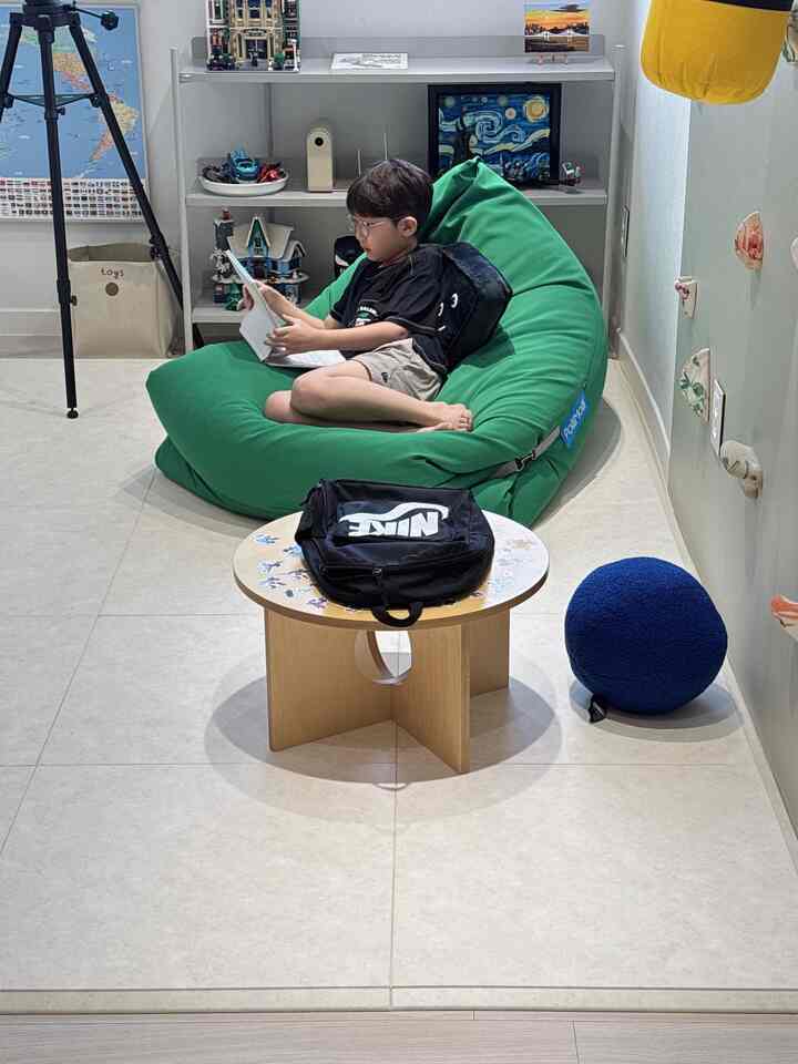 グリーンのビーズクッションと木製テーブルが配置された子供部屋、温かみのある雰囲気のあるインテリア