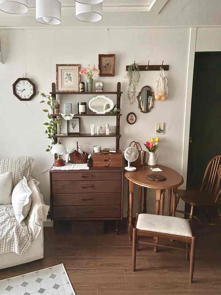 ホワイトと木目調の色調のリビング、ヴィンテージ家具やソファ、小さな木製テーブルが配置された雰囲気のあるインテリア