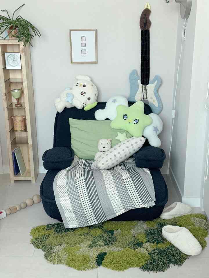 ナチュラルカラーとグリーンのトーンのリビング、ダークネイビーのアームチェアと多様なクッション、ラグが心地よい雰囲気を作る空間