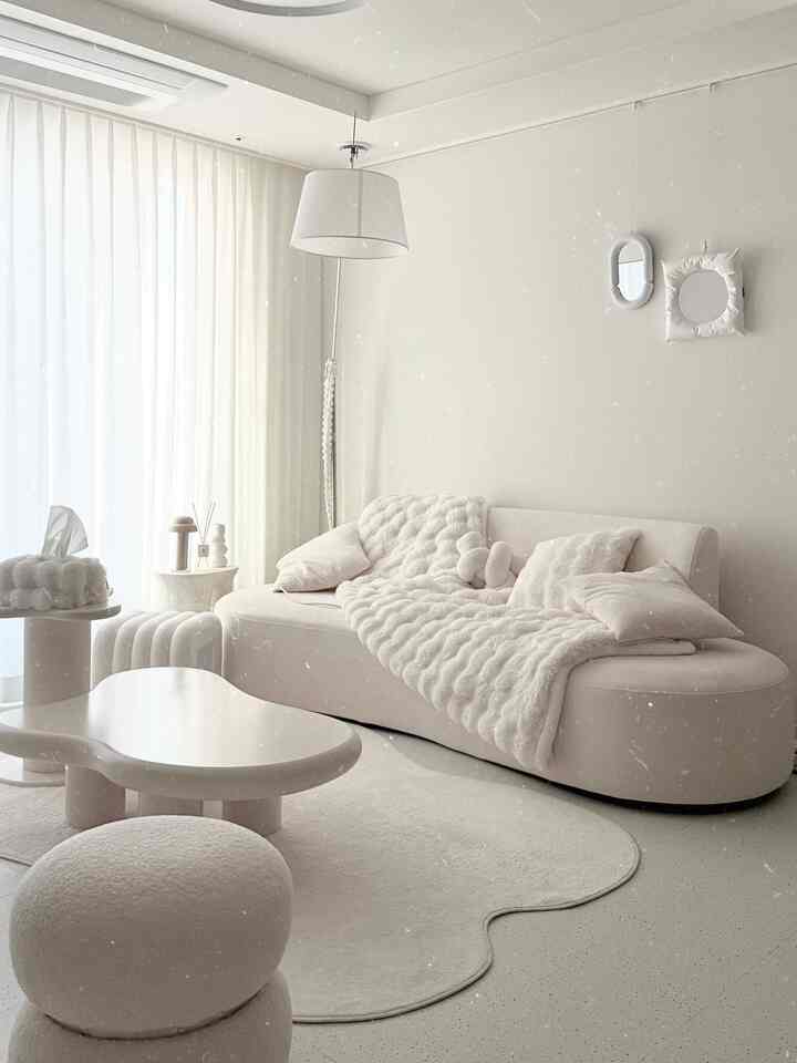 ベージュとホワイトの色調のリビング、柔らかい曲線のソファとラグ、フロアランプが配置されたシンプルで自然な雰囲気のインテリア