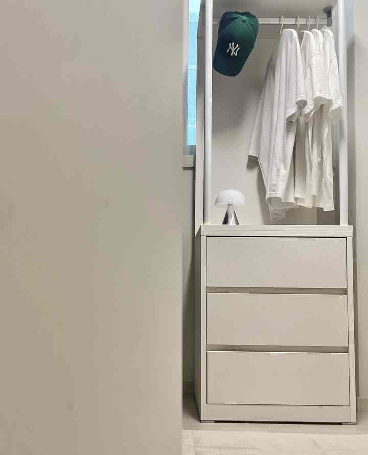 暖かみのあるクリームホワイトのウォークインクローゼットに、ドレッサーとハンガーラックが配置されたモダンで整った収納空間