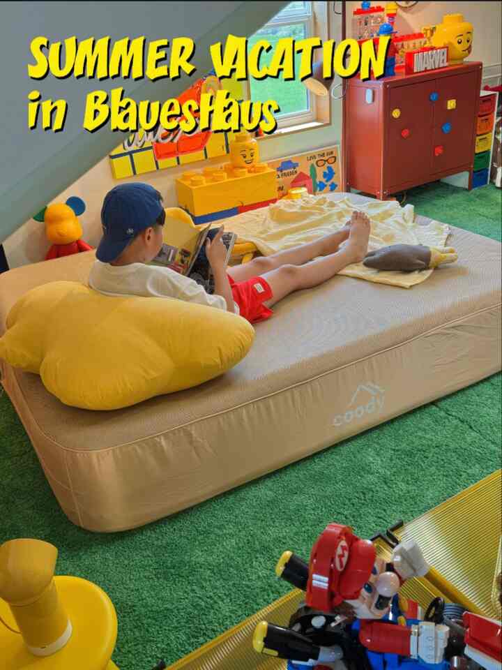 緑色のカーペットとベージュのマットレスが敷かれたロフトの子供部屋、黄色のクッションと多彩なおもちゃが配置された雰囲気のあるインテリア