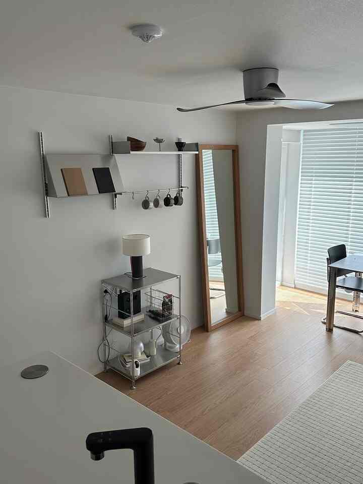 白と木目調が調和した清潔感のあるダイニング、ミニマルな収納棚と全身鏡が配置された印象的な空間