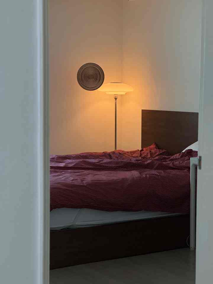 赤い寝具と木製ベッドが配置されたモダンな寝室、温かみのある照明が居心地の良い雰囲気を演出するインテリア