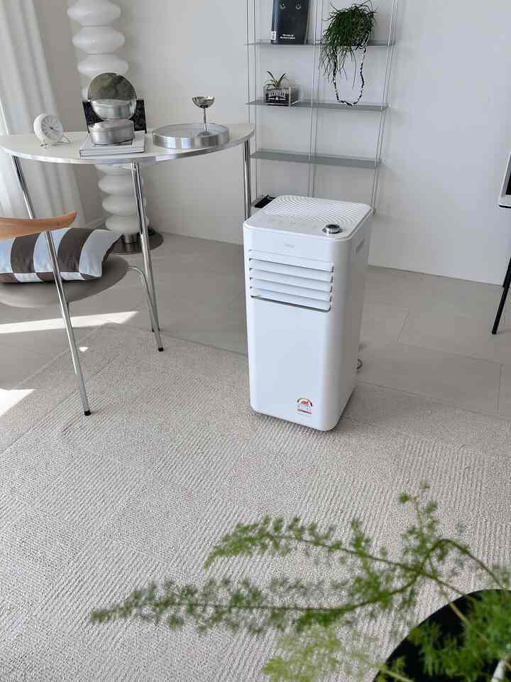 白とナチュラルカラーのシンプルなリビング、カーペットの上に空気清浄機とテーブルランプが配置された快適なインテリア