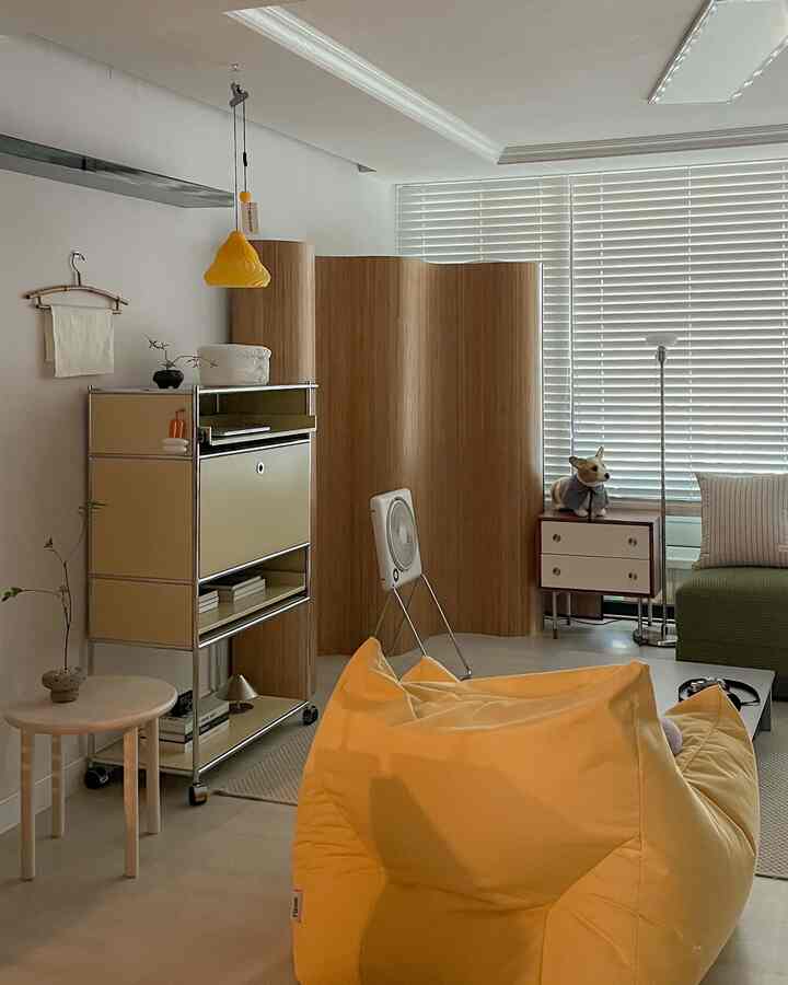 白と木目調が調和するリビング、黄色のビーズクッションとミッドセンチュリーモダンの間仕切りが配置された雰囲気のある空間