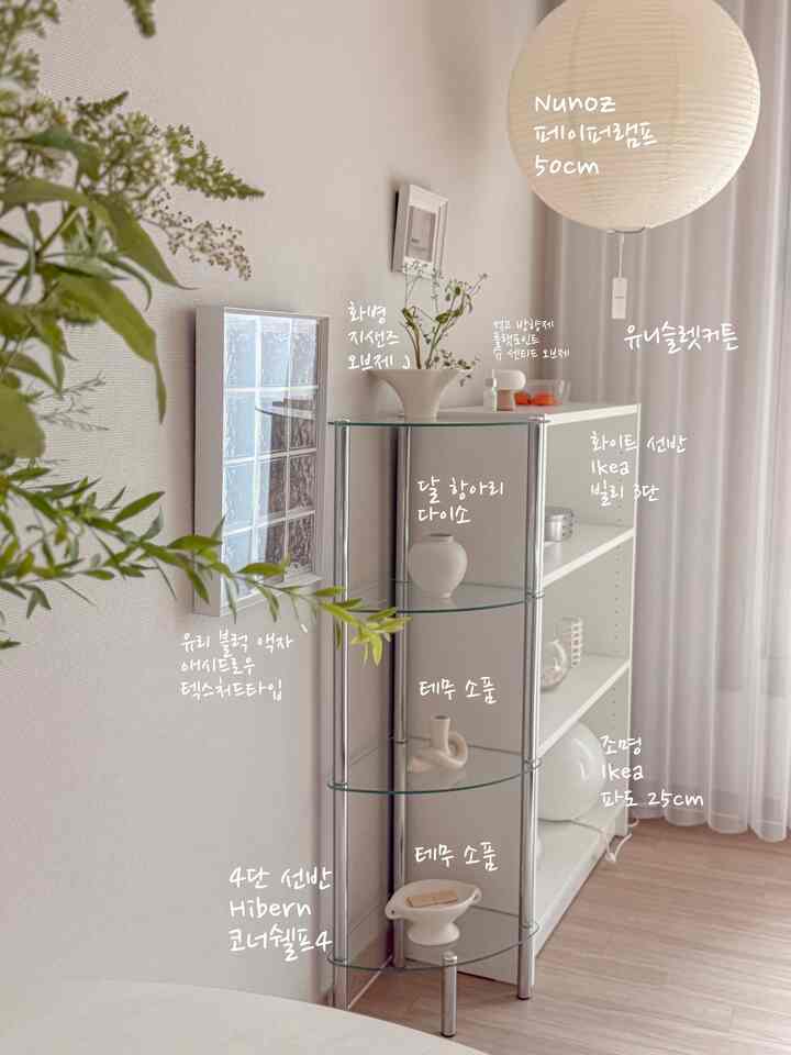 白を基調としたリビング、イケアのビリー3段棚とハイバーンのコーナー棚が配置され、ペーパーランプ照明と植物が調和したモダンなインテリア