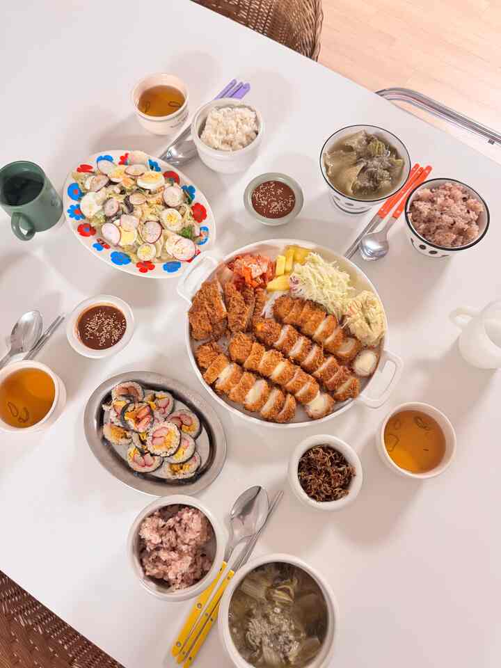 白いテーブルの上に多彩な皿と飯碗が並ぶシンプルでナチュラルなダイニング空間