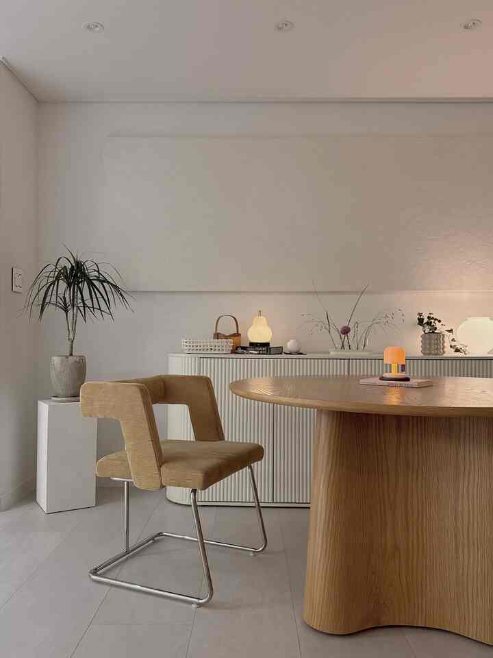 白い壁と木製の丸いダイニングテーブル、ベージュの椅子が配置されたナチュラルでシンプルなダイニングルーム