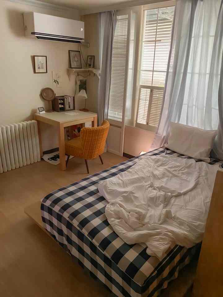 ナチュラルな色調の寝室、ロータイプベッドと木製デスク、黄色い椅子が配置されたシンプルで温かみのある空間