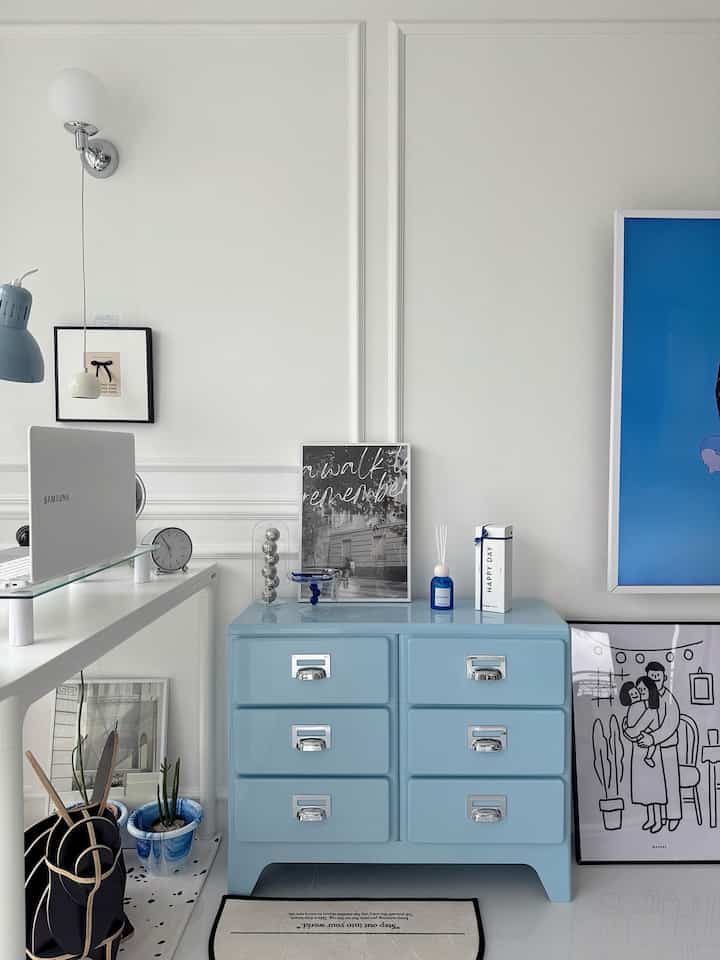 白とスカイブルーの色調のリビング、ブルーのチェストが中央に配置された清潔でモダンな雰囲気のインテリア