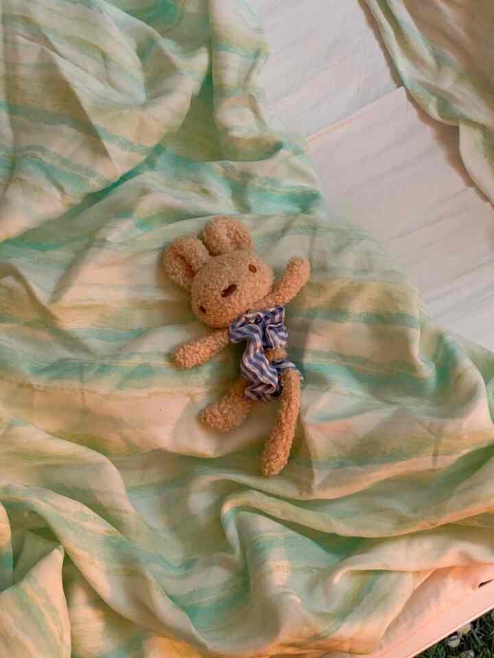 パステルグリーンとアイボリーの寝具が置かれた寝室、上に赤ちゃん用のぬいぐるみが乗っている雰囲気のあるインテリア