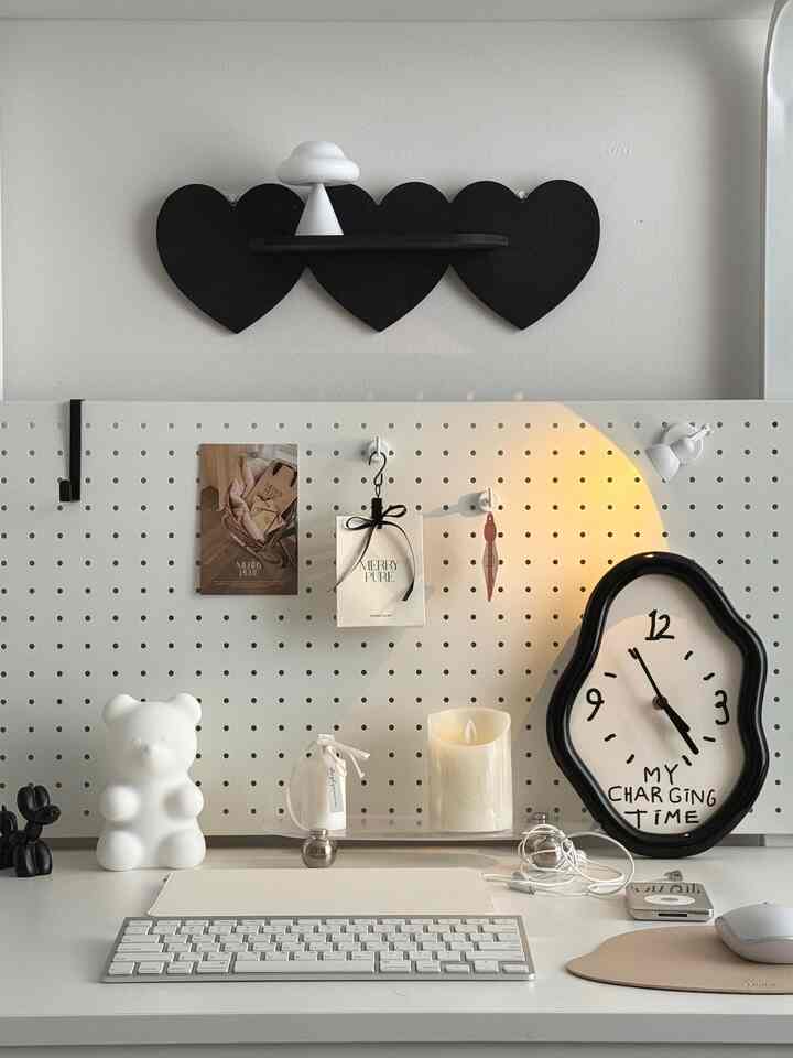 White and black toned home office space featuring a minimalist desk with keyboard, mood light, and uniquely designed clock in a neat work environment