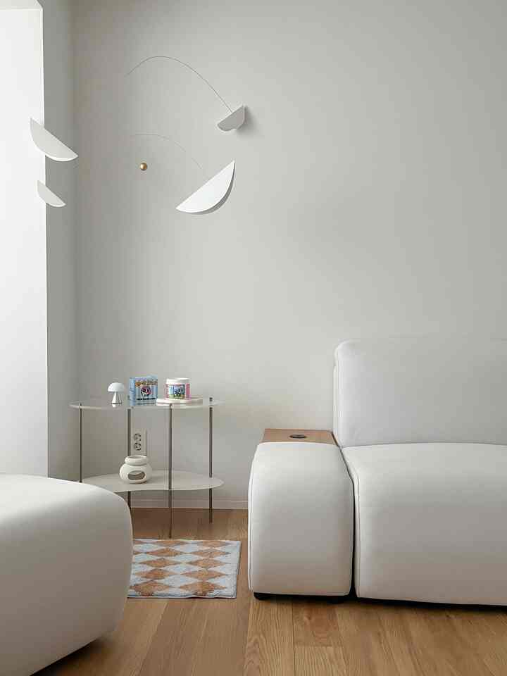 ホワイトと木目調のリビング、シンプルなソファとサイドテーブル、モビールが配置された落ち着いた雰囲気のインテリア