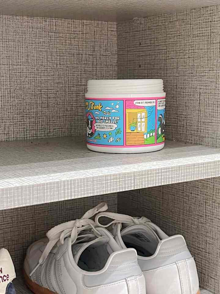 グレー調の靴棚に白いスニーカーと固体消臭剤が置かれた空間