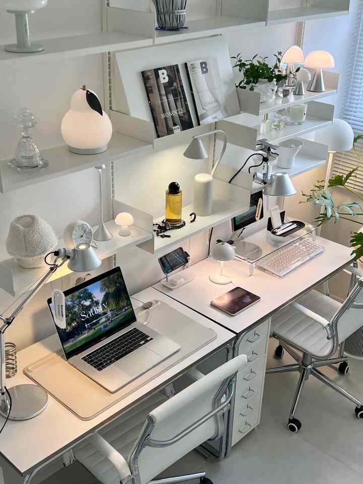 ホワイトとシルバーのトーンでまとめられたモダンなホームオフィス、机が二つ、オフィスチェア、照明や棚が整然と配置された印象的な空間