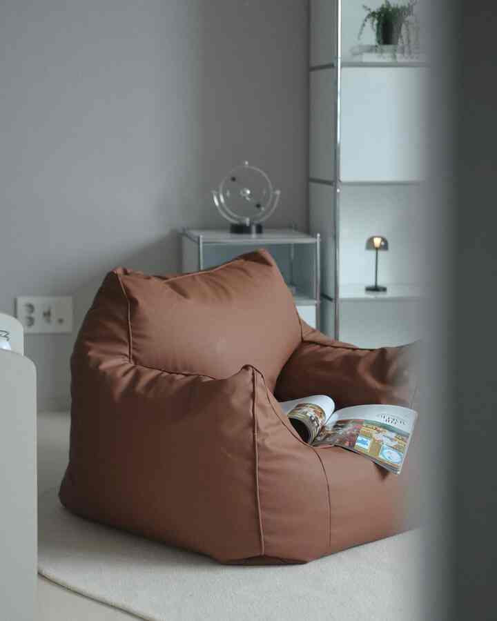 A simple and natural living room featuring a soft brown bean bag sofa and beige rug