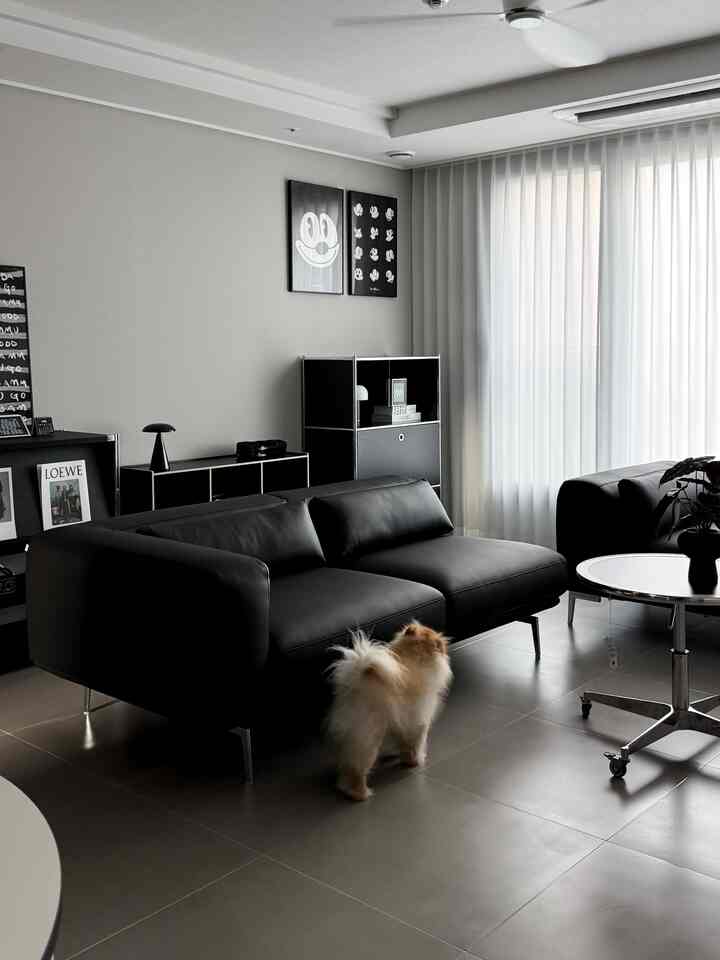 A black-toned living room featuring a black leather sofa and simple storage units with a modern and minimal atmosphere