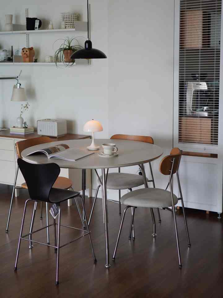 A modern dining room in white and brown tones featuring a round dining table and various dining chairs