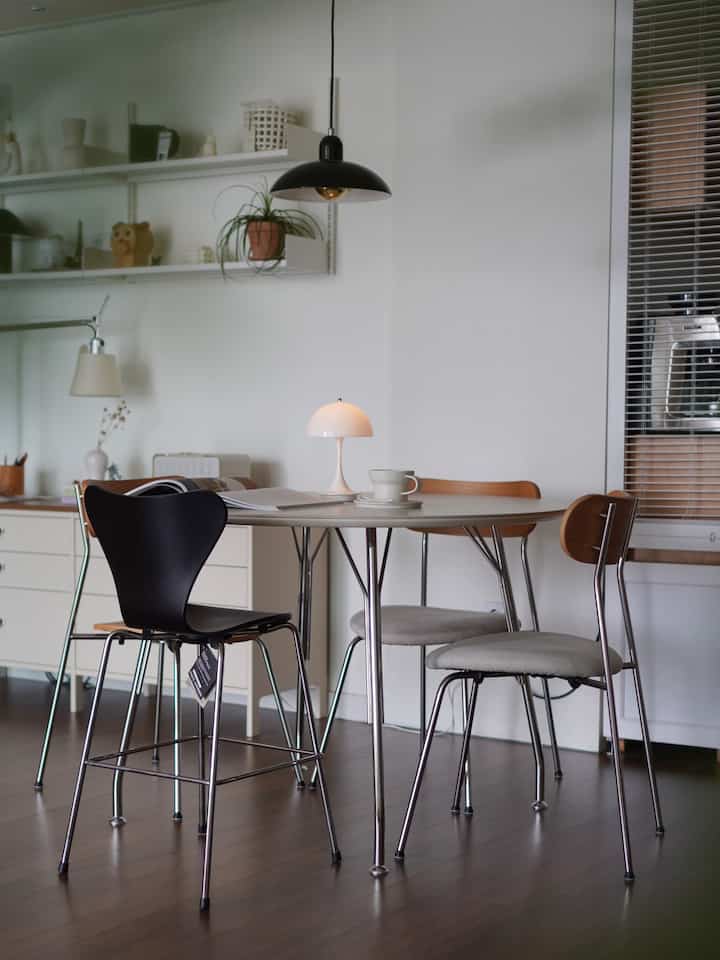 Natural modern dining room with white, black, and wood tones featuring a round dining table and assorted chairs