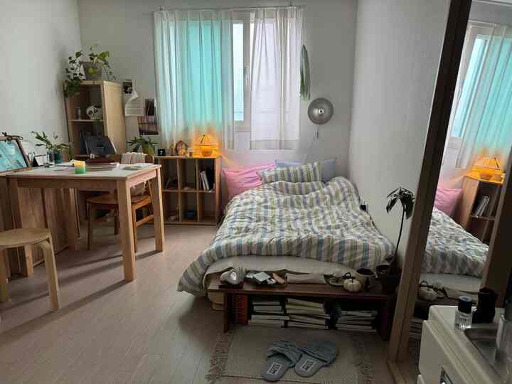 ナチュラルウッド調とパステルブルーのカーテンが配置された一人暮らし用寝室、落ち着いた居心地の良い空間