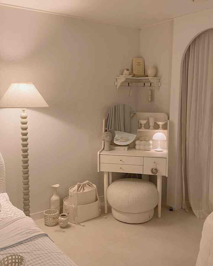 ベージュとホワイトの色調の寝室、丸いスツールと化粧台、柔らかなムード照明が配置されたナチュラルな雰囲気のインテリア