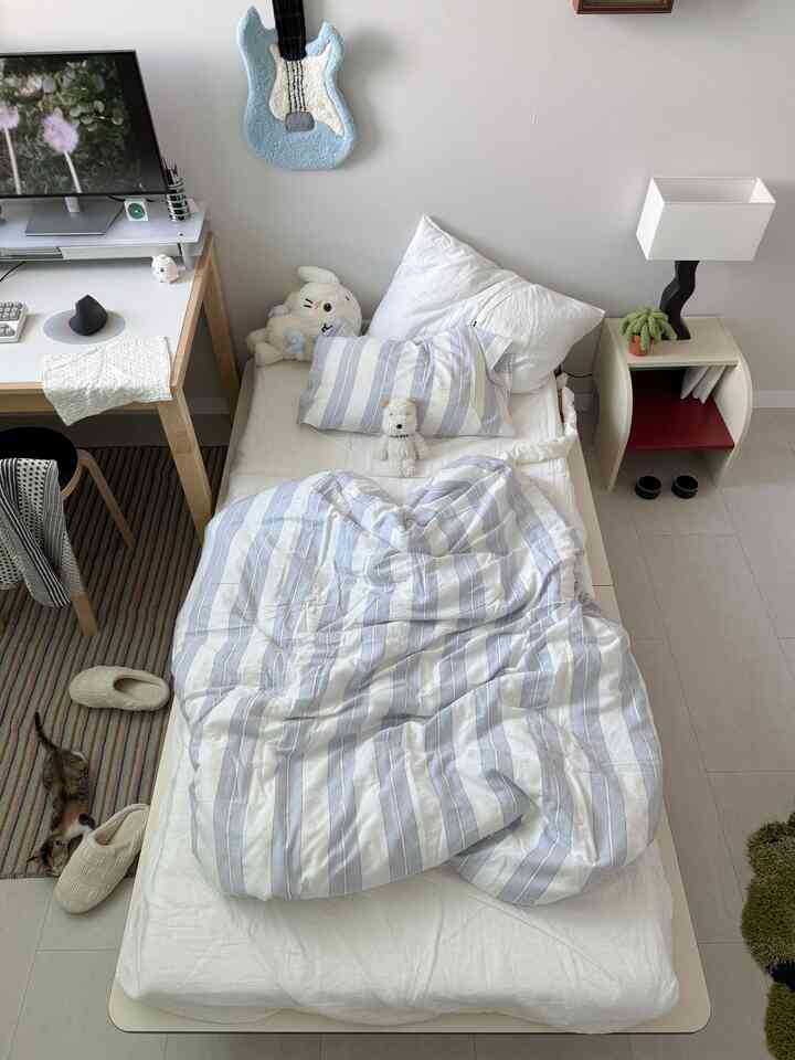 白とナチュラルカラーの一人暮らし用寝室、ベッドとデスク、ペット用アイテムが配置された落ち着いた雰囲気のインテリア