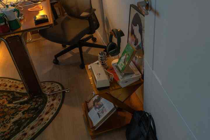 茶色のトーンのホームオフィス、デスクとオフィスチェア、本棚に本とヘッドセットが配置された雰囲気のある空間