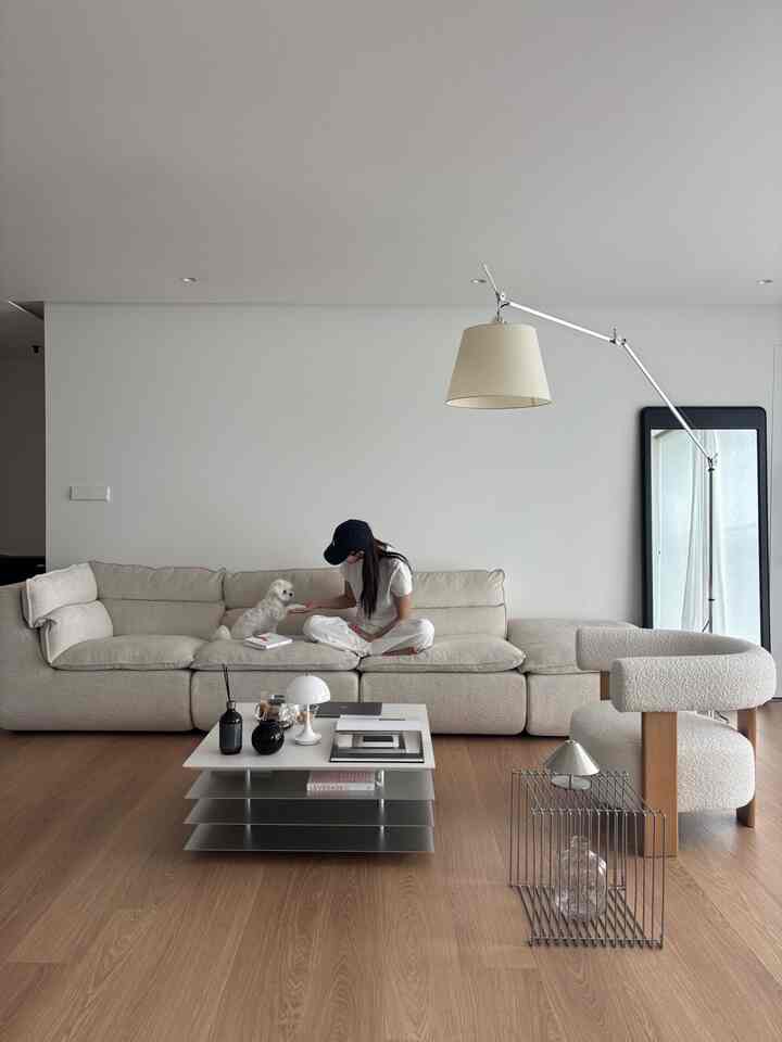 ナチュラルな木目調の床と白いソファ、アームチェアが配置されたペットと暮らす二人用のリビングルーム