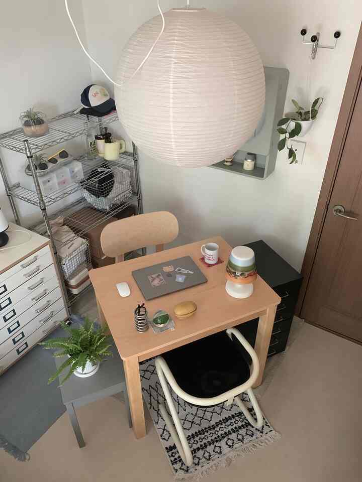 ナチュラルカラーとホワイト調の一人暮らし用ホームオフィス、木製デスクとチェア、ペンダントライトが配置された印象的な作業空間