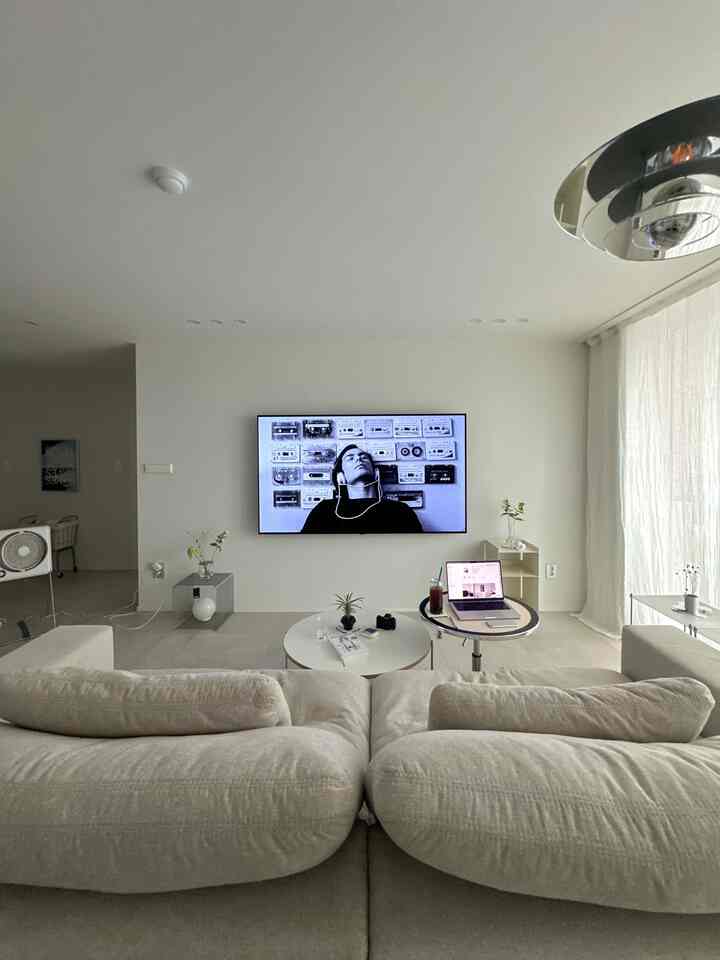 白とアイボリーのトーンのリビング、中央にソファと丸いコーヒーテーブルが配置されたナチュラルモダンな雰囲気のインテリア