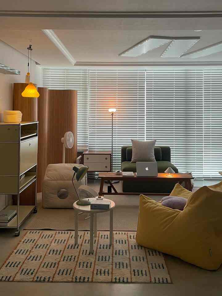 ベージュとイエローの色調のリビング、木製ベンチとビーンバッグが配置された落ち着いた空間