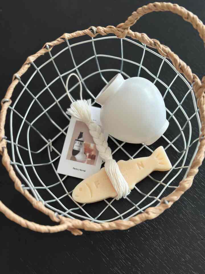 黒いワイヤーバスケットに白いオブジェが配置された、清潔感あるバスルームアイテムの写真