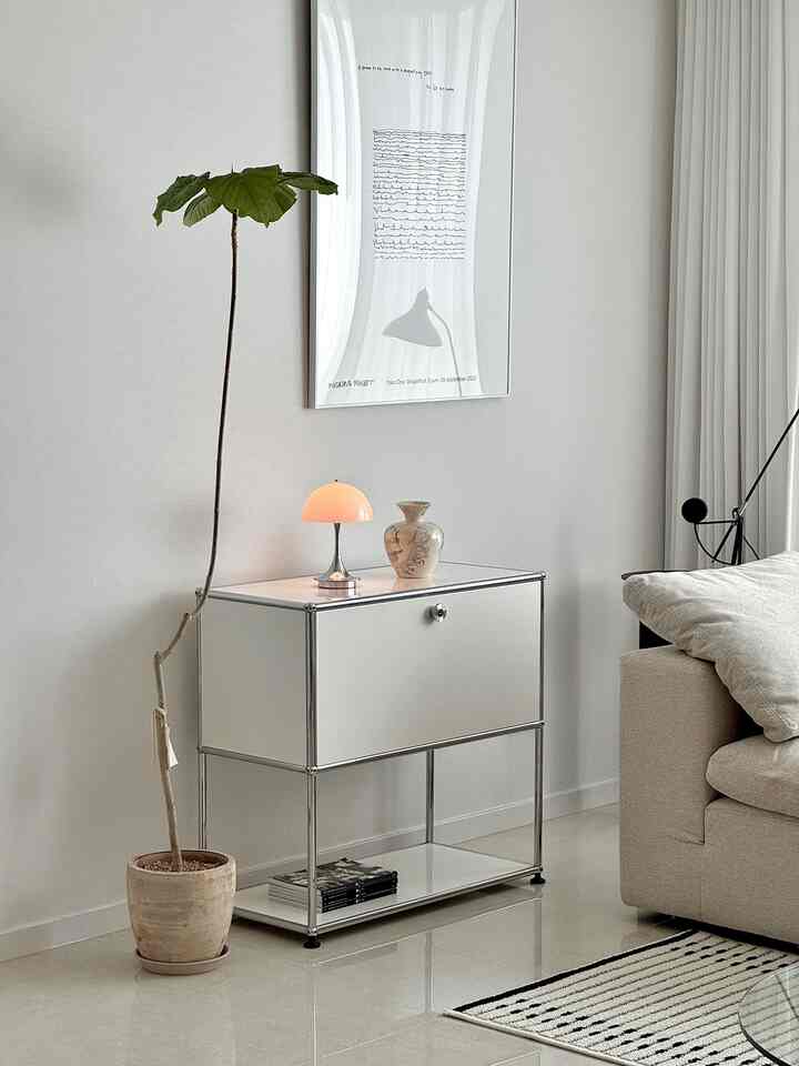 白とシルバーのモダンなリビング、シンプルなキャビネットとフロアランプ、大きな観葉植物が配置された清潔感のある空間