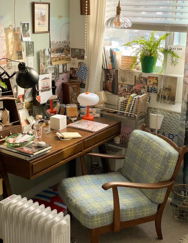 自然光が差し込むヴィンテージ風の木製デスクと快適な椅子が配置されたホームオフィス