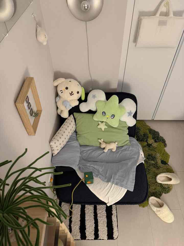 ネイビーブルーのソファとグリーンクッション、赤ちゃんのぬいぐるみが配置された居心地の良い一人暮らしのリビング